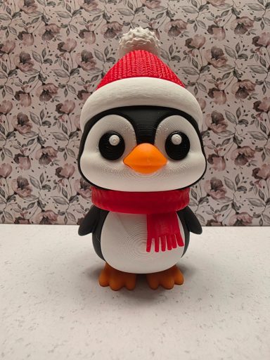 Kuscheliger Pinguin mit rotem Hut und Schal vor einem gemusterten Hintergrund.